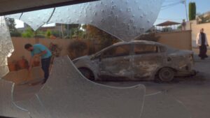 Photo: A Palestinian resident sweeps shards of glass next to burnt cars that were set on fire by Israeli settlers during an attack on the town of Turmus Ayya on 21 June 2023. Eddie Gerald/Alamy Live News